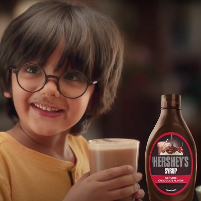 Boy smiling after drinking HERSHEY'S Chocolate flavored SYRUP mixed with Milk